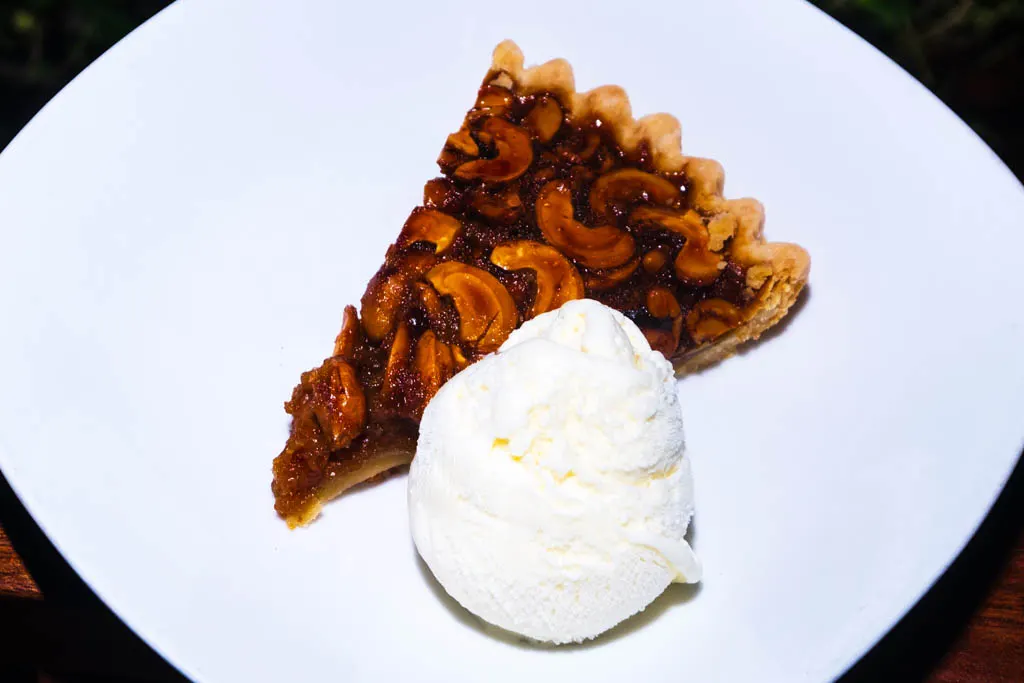 A slice of cashew pie with ice cream