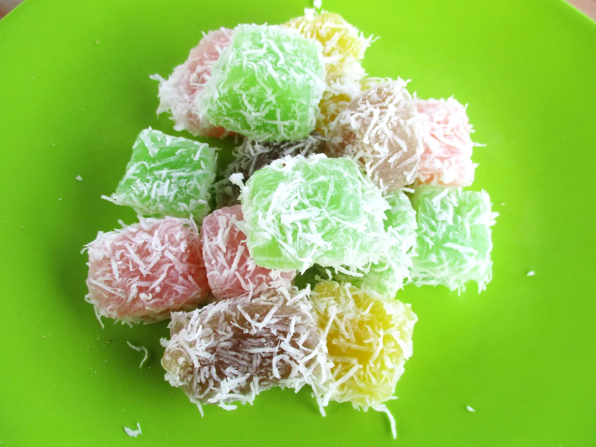 Small colourful Balinese cakes rolled in grated coconut, piled on a plate