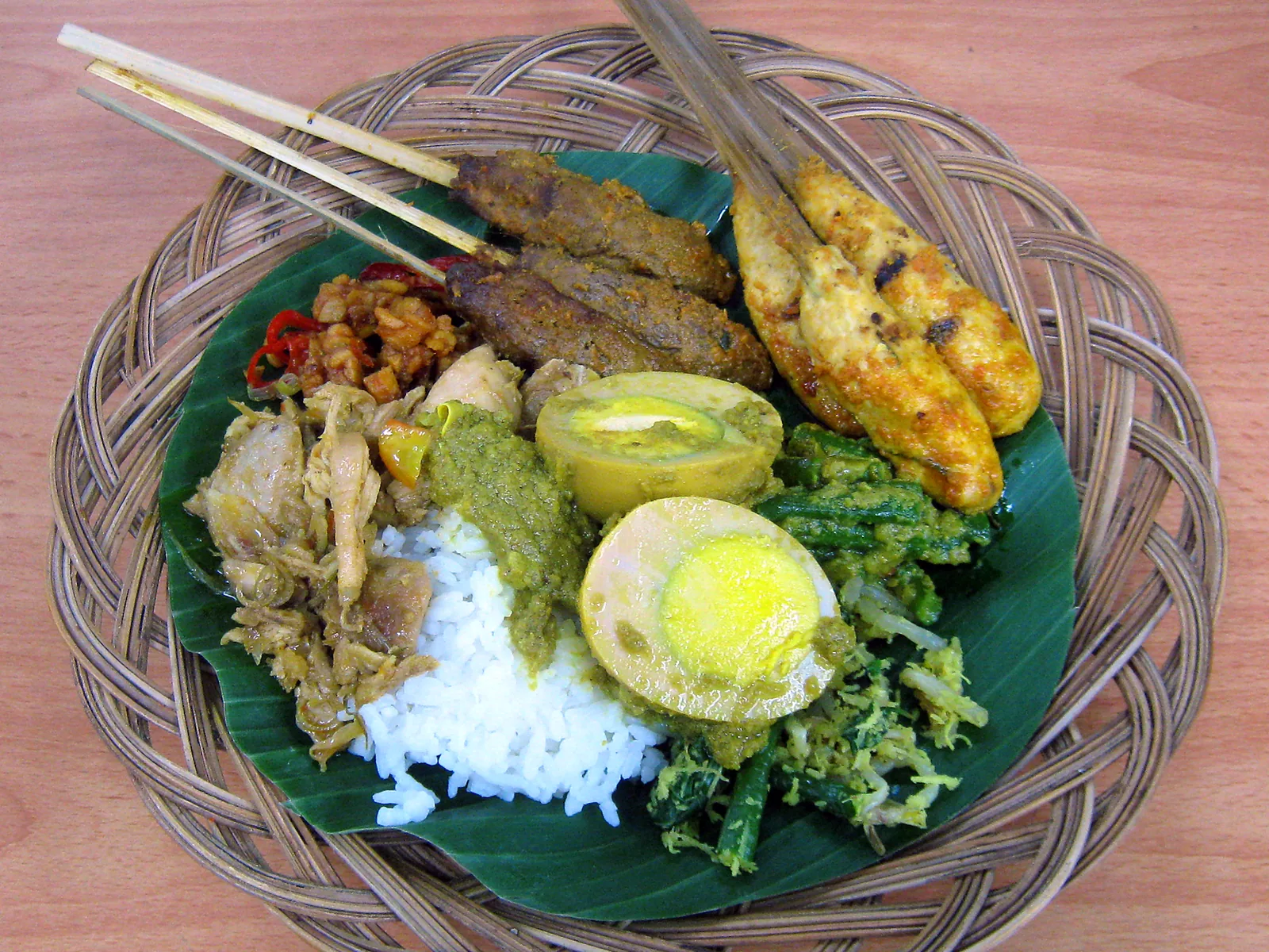 Balinese nasi campur on a banana leaf: rice, sate lilit, egg, chicken and vegetables