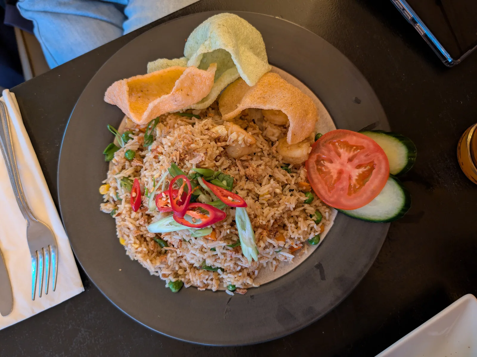 Plate of prawn nasi goreng with prawn crackers, tomato and chillies
