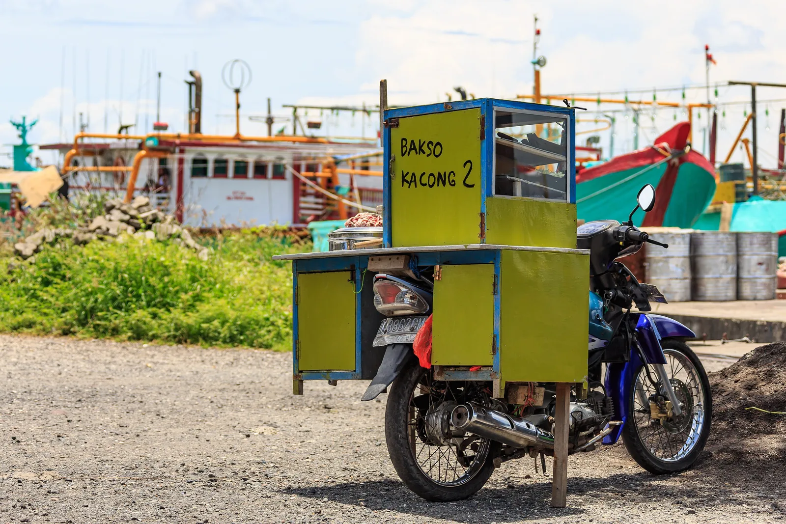 Motorbike fitted with a small glass-fronted bakso kitchen, parked at Benoa harbour