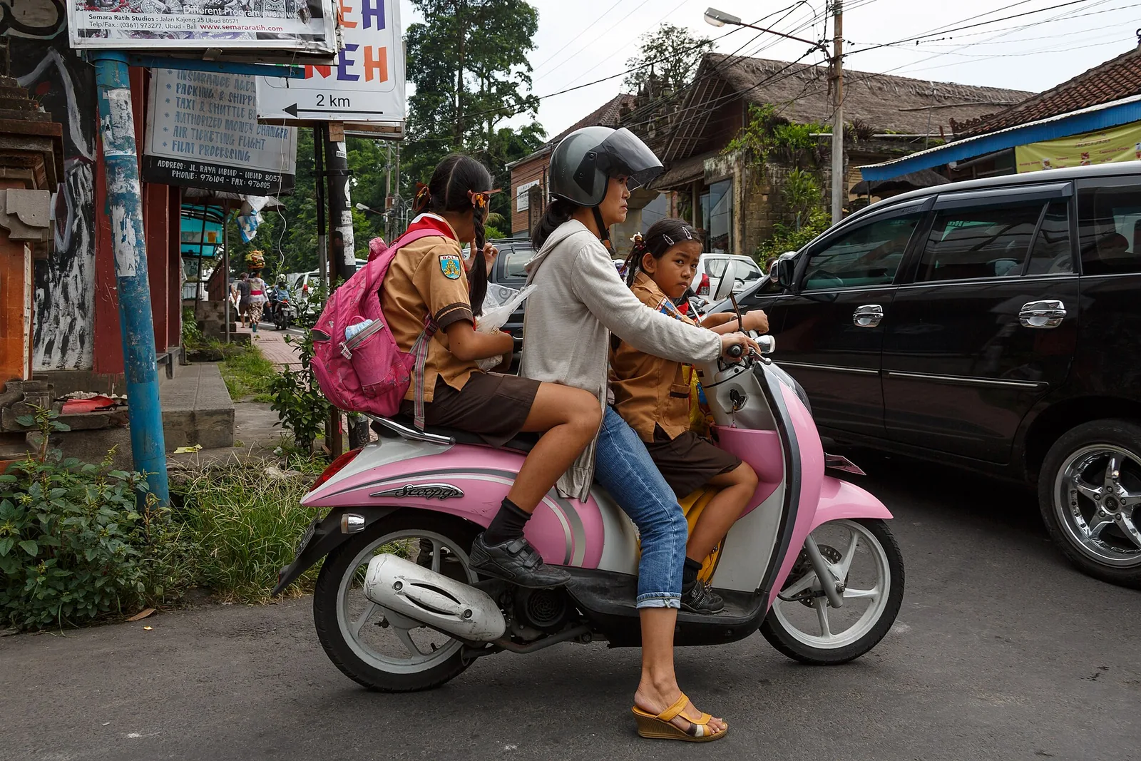 Three passengers on a pink scooter on Ubud’s main street